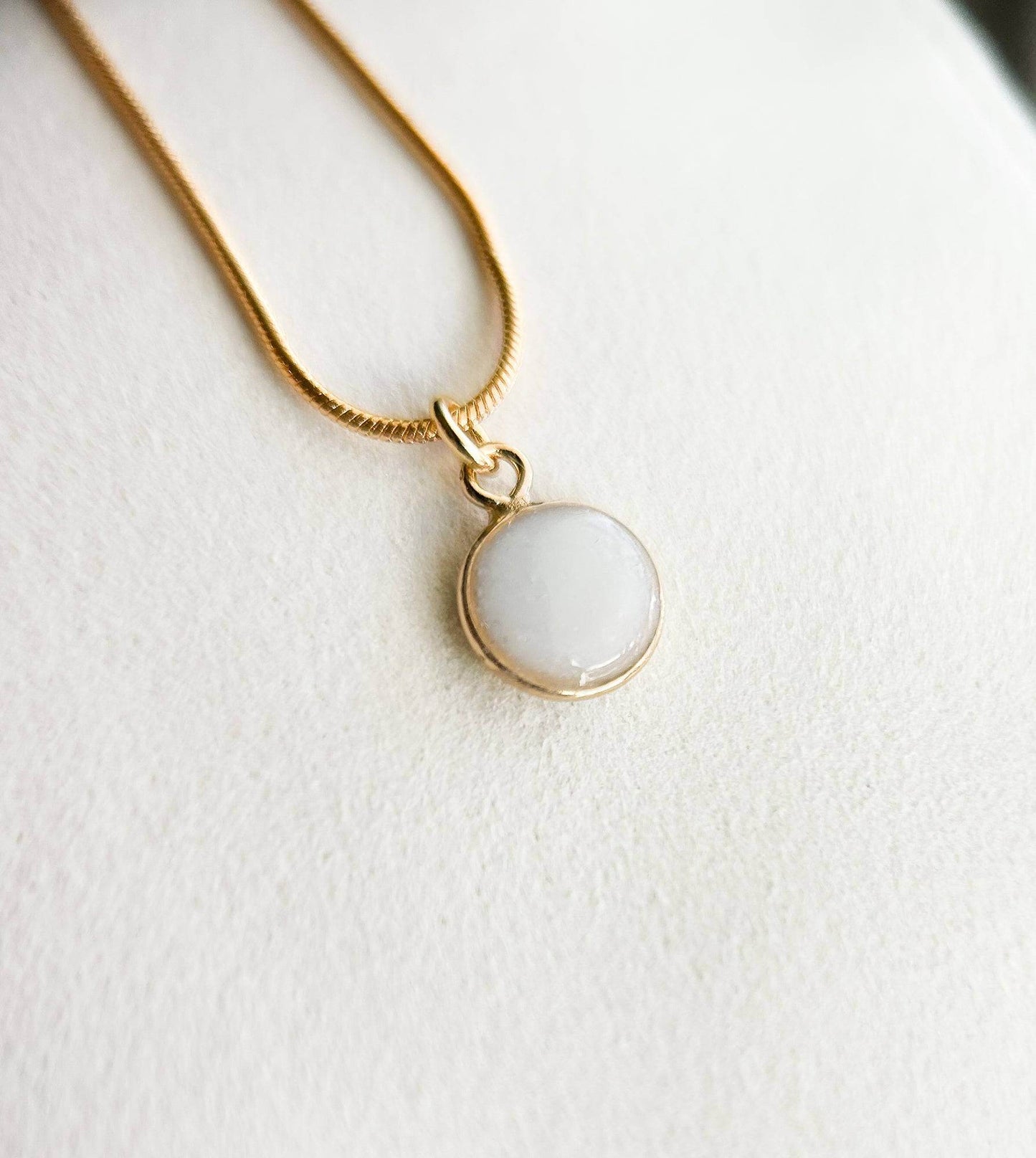 Breastmilk jewelry in a ball with gold chain.