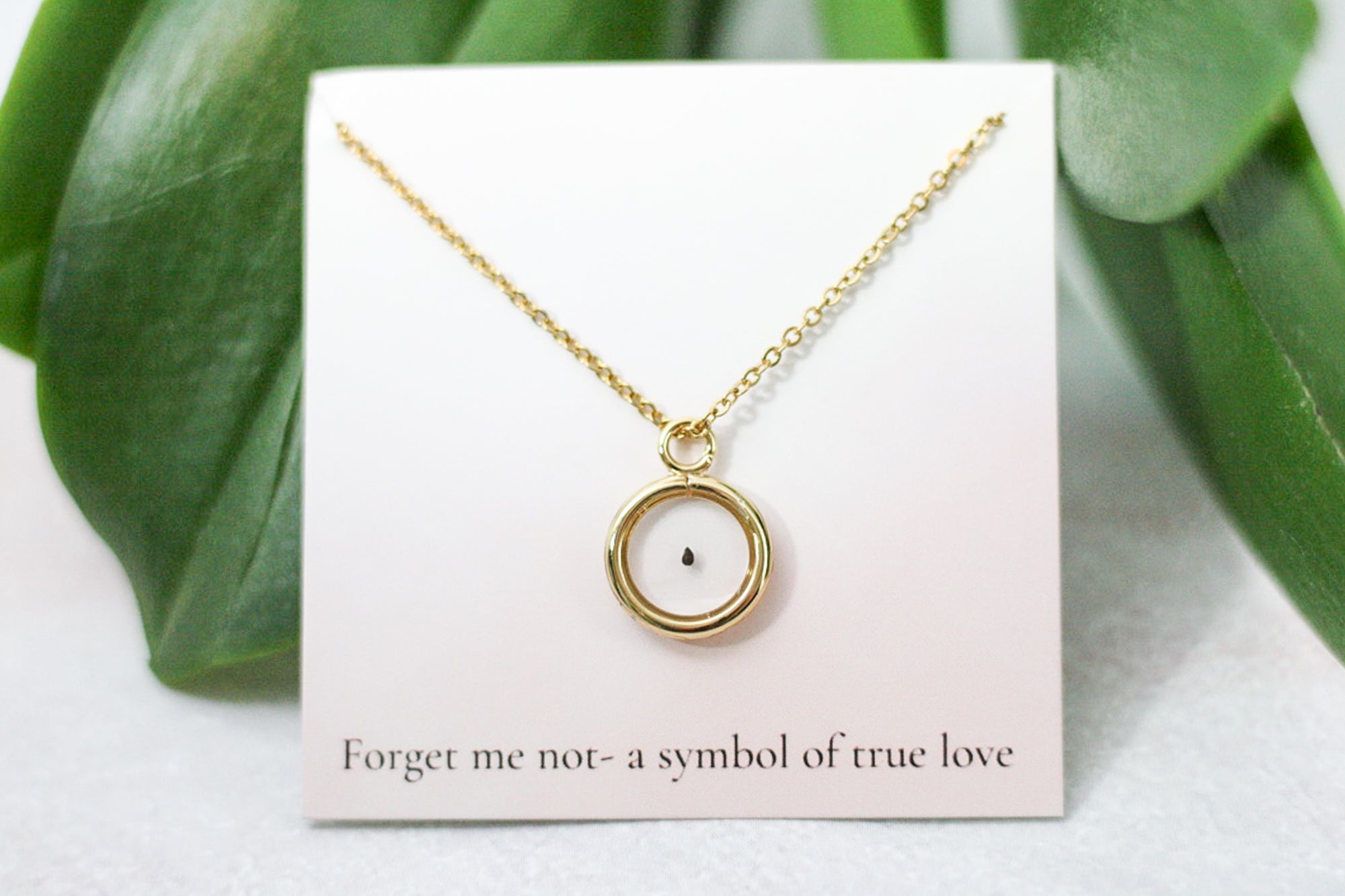 forget me not seed in gold pendant necklace on card reading 