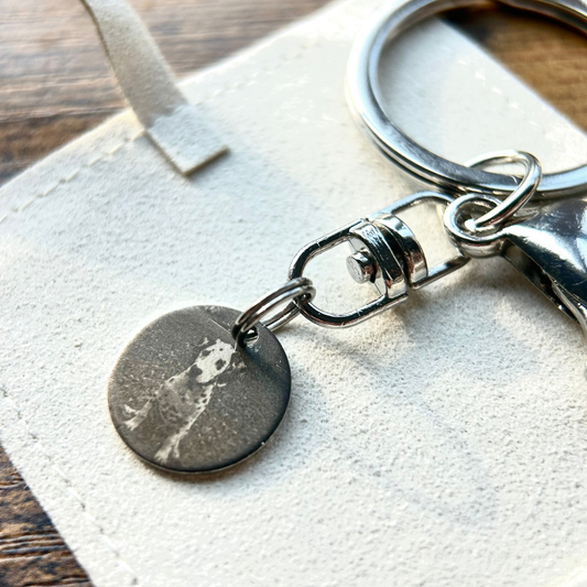Rest of the Nest Keychain with a round metal tag on a wooden surface