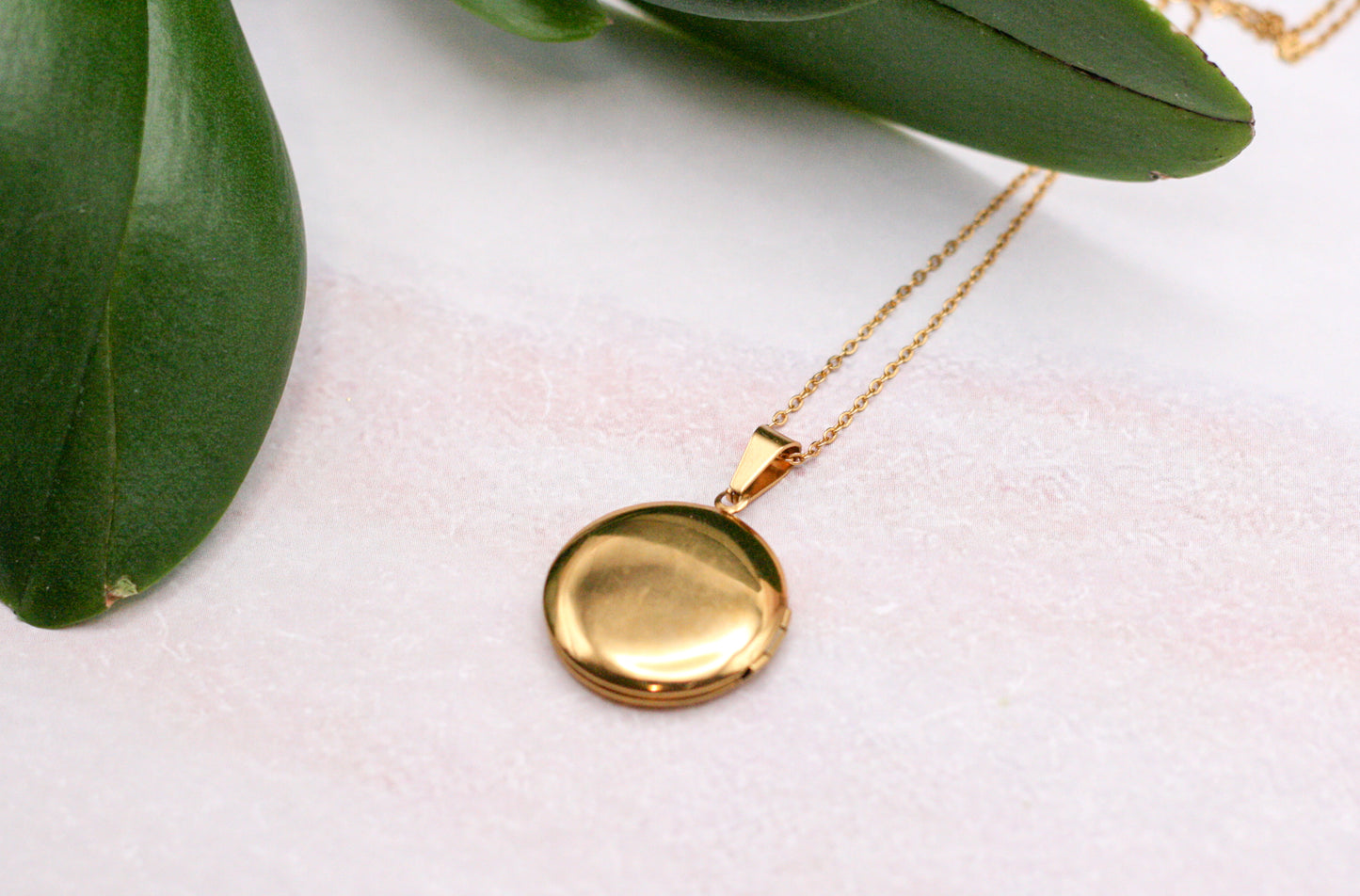 closed gold locket with green leafs