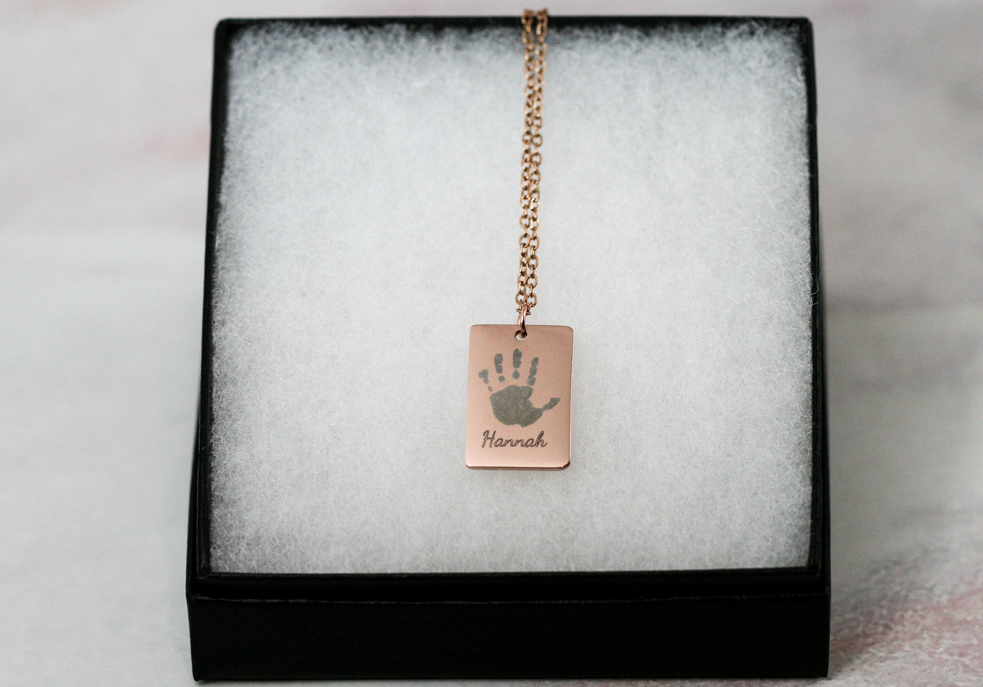 Handprint necklace in rose gold on black jewelry box