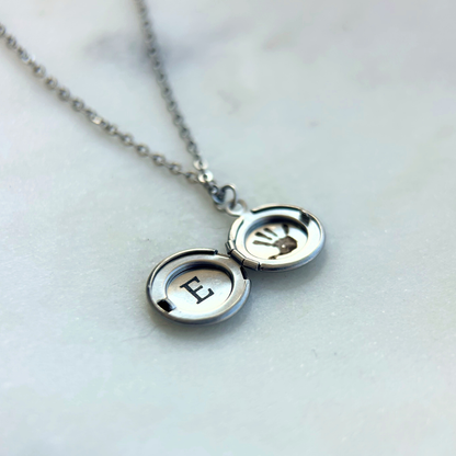 Rest of the Nest silver necklace with a locket featuring an engraved letter 'E' on a light background