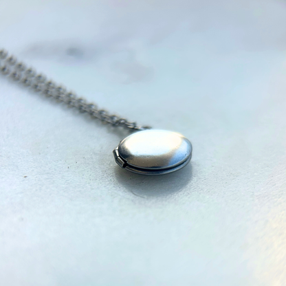 Rest of the Nest mini handprint locket closed on light background