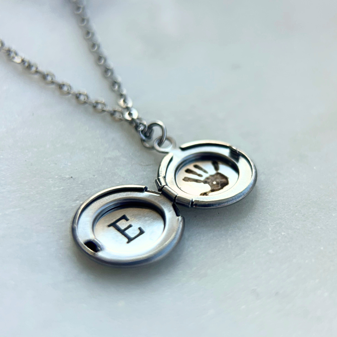 Rest of the Nest mini handprint locket open on a marble backdrop