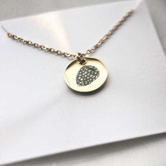 Gold necklace with a round pendant on a white surface