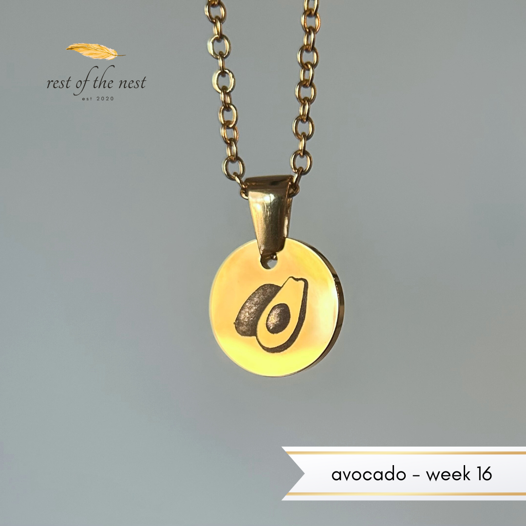 Rest of the Nest Gold necklace with avocado pendant on a gray background