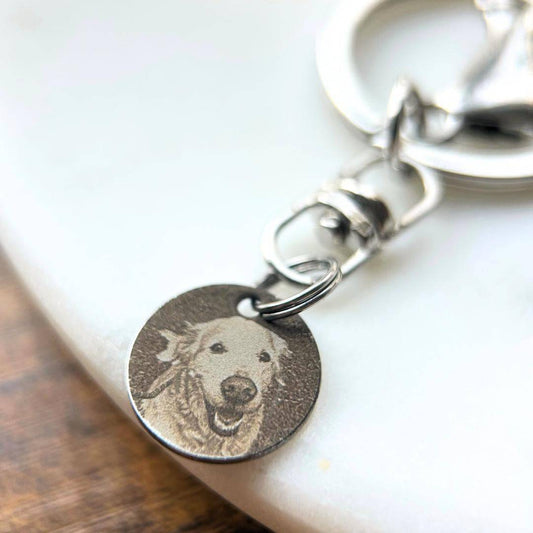 Rest of the Nest Keychain with a circular tag featuring a dog's face engraved on a white surface.