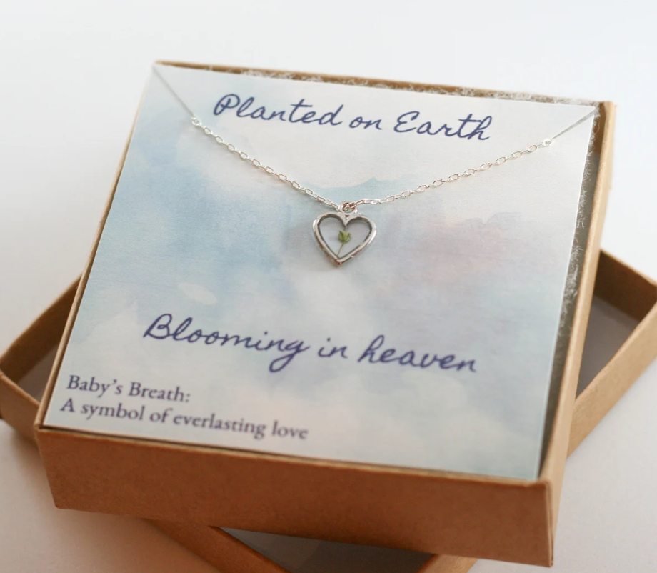 one piece of babys breath in a silver heart pendant necklace with a card reading "planted on earth blooming in heaven"