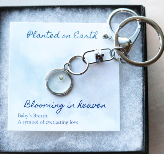 silver keychain with a piece of babys breath on a card reading "planted on earth blooming in heaven"