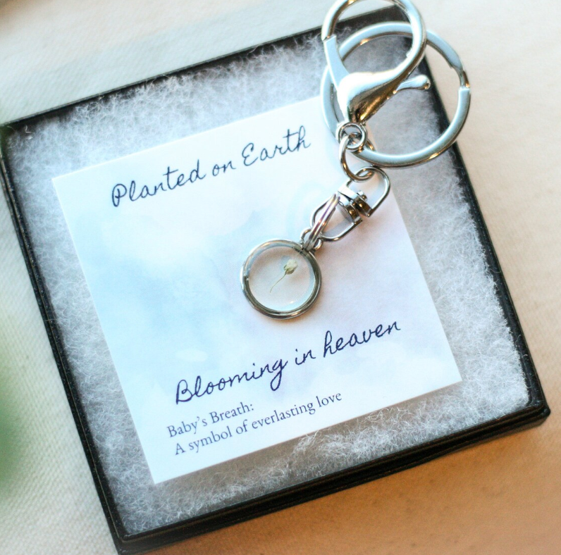 silver babys breath keychain on a card reading "planted on earth blooming in heaven" in a black necklace box