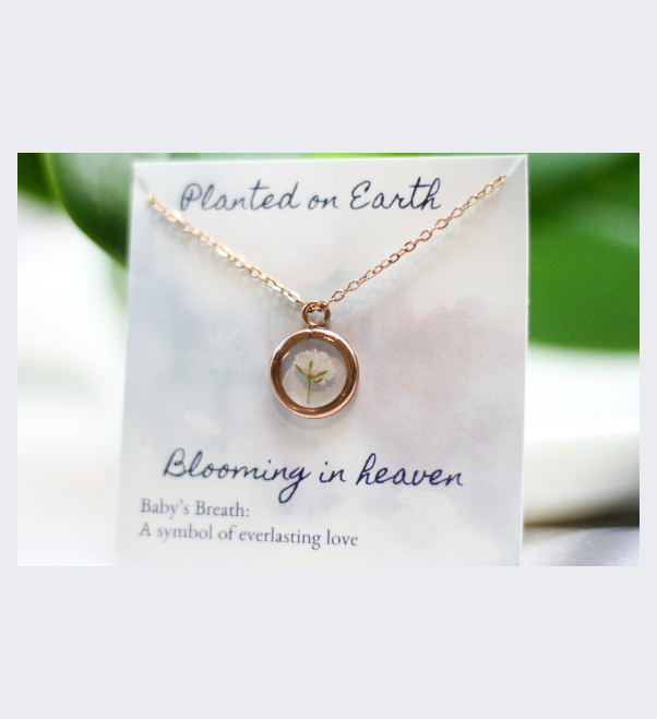 one piece of bloomed babys breath in a rose gold pendant necklace with a card reading "planted on earth blooming in heaven"