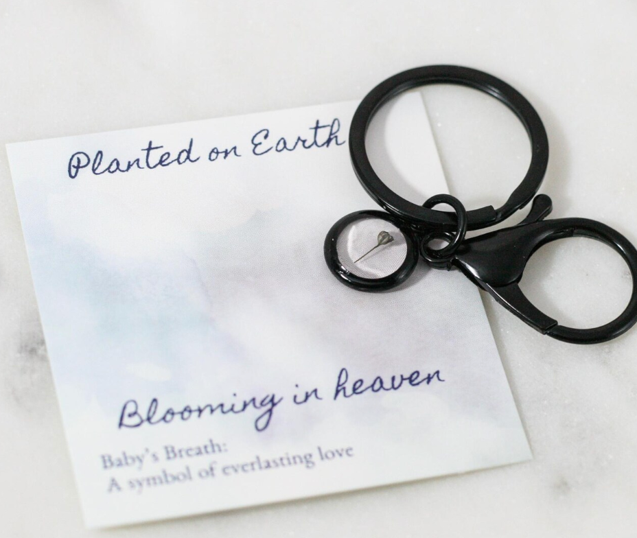 black matte babys breath keychain on a card reading "planted on earth blooming in heaven"