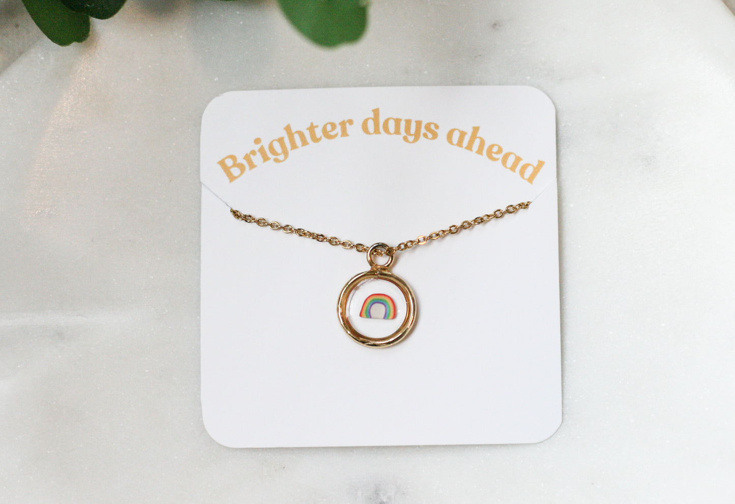 gold pendant with a clay rainbow inside on a card reading "brighter days ahead"