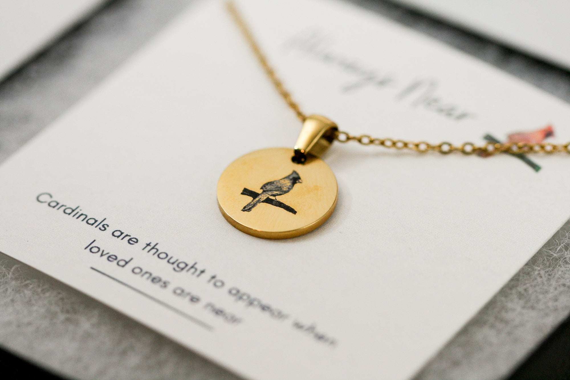 gold cardinal pendant necklace on a card with a cardinal reading 