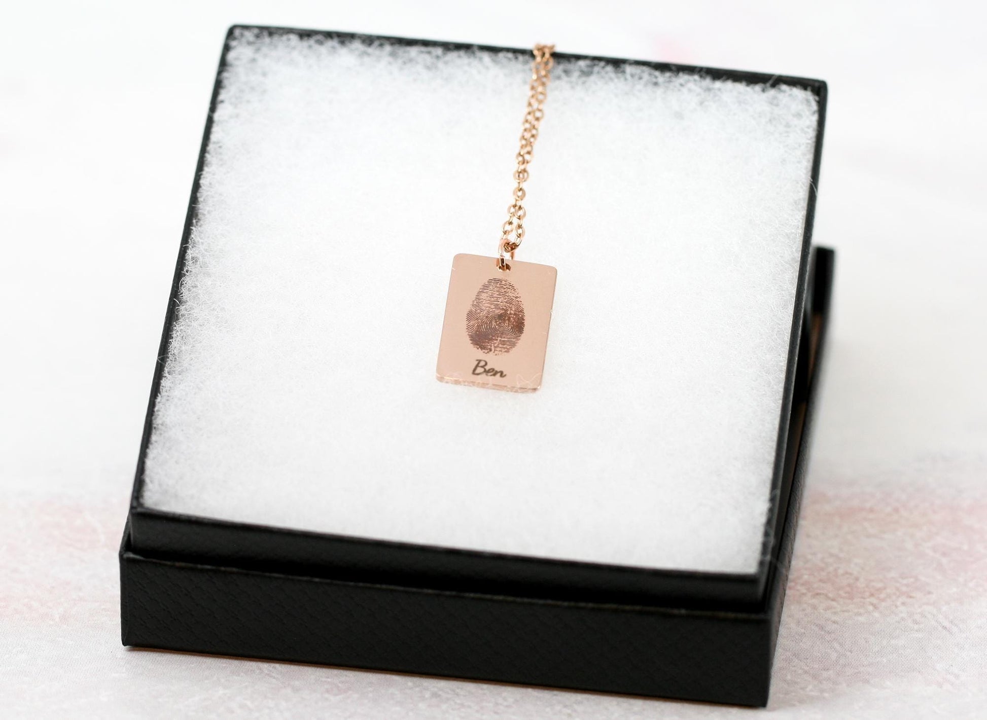 thumbprint necklace in rose gold with the name "Ben" under it in a black necklace box