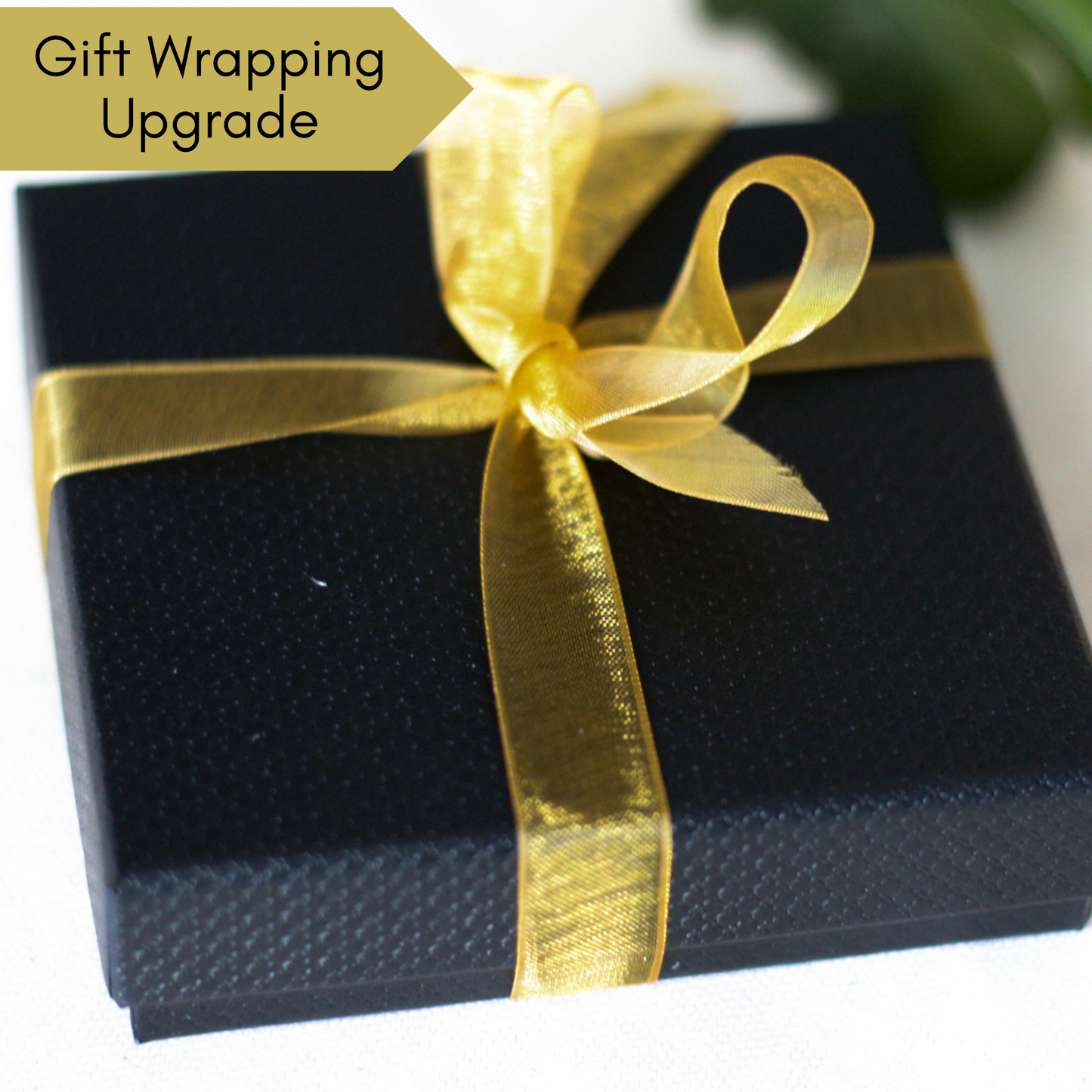 Gift wrapping upgrade example of a Black necklace box tied with a gold ribbon 