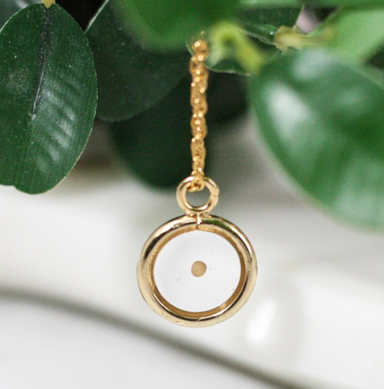 gold mustard seed necklace with plant leafs in the background