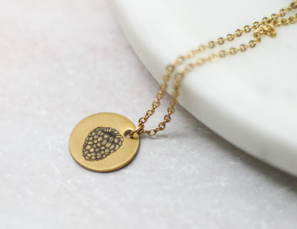 up close view of raspberry necklace engraved onto gold pendant