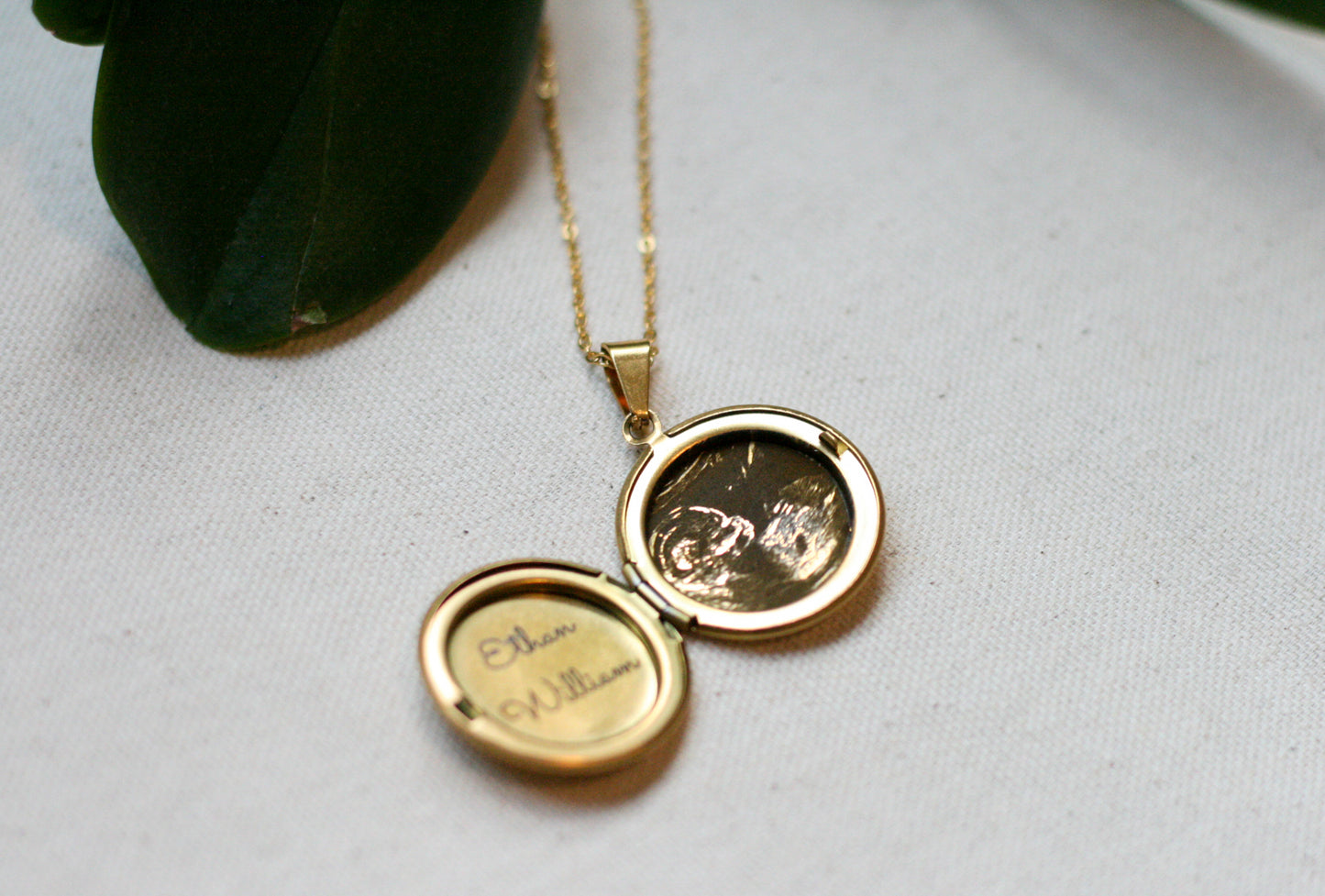 gold locket open with a sonogram and name engraved in it 