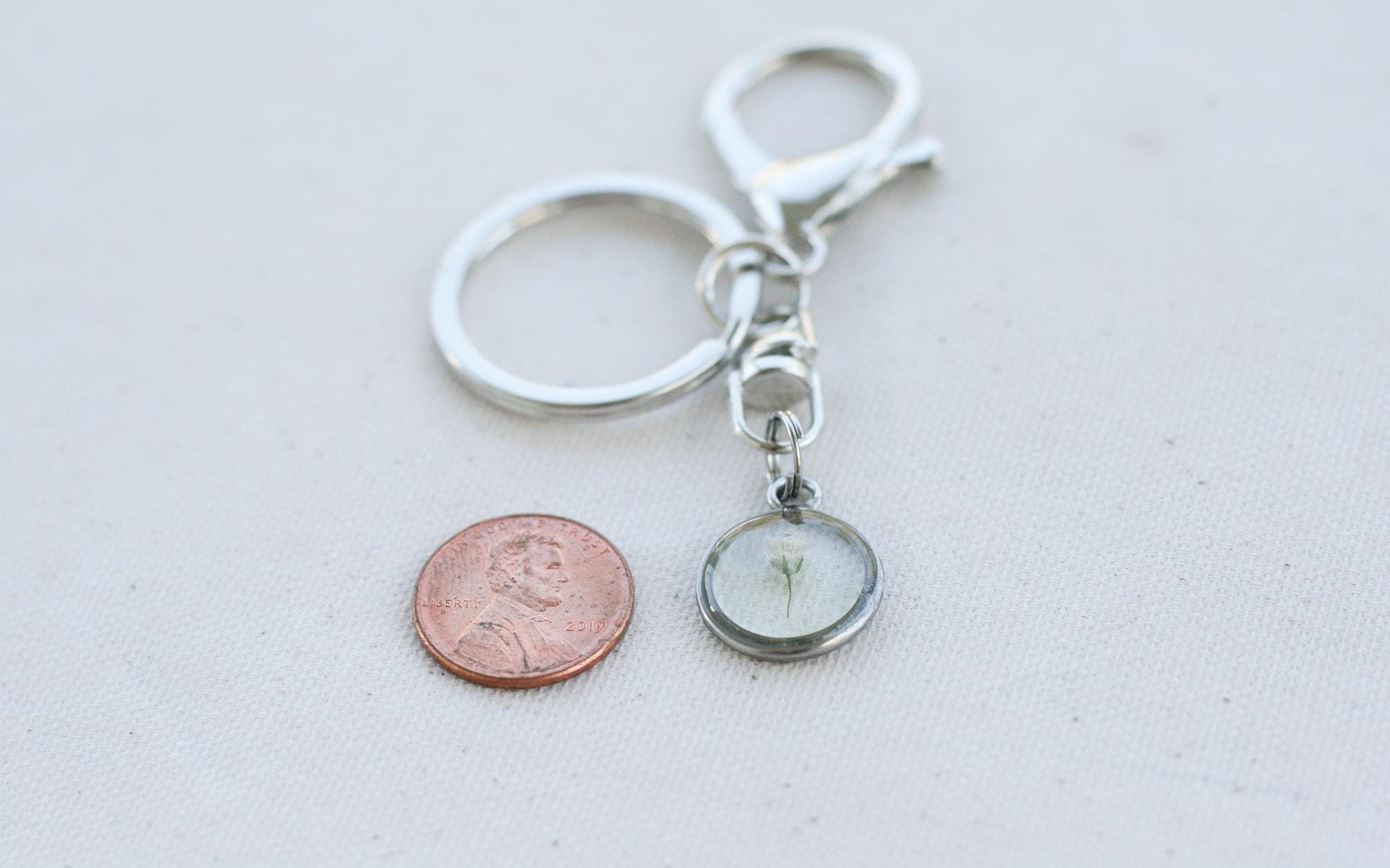 babys breath keychain next to a penny for size