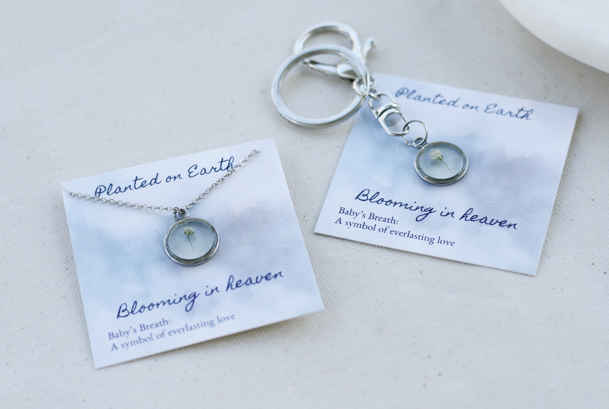 babys breath necklace and keychain in silver on "planted on earth blooming in heaven" cards