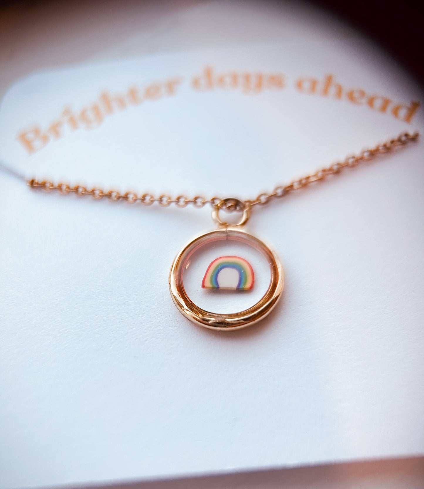 gold pendant with a clay rainbow inside on a card reading "brighter days ahead"