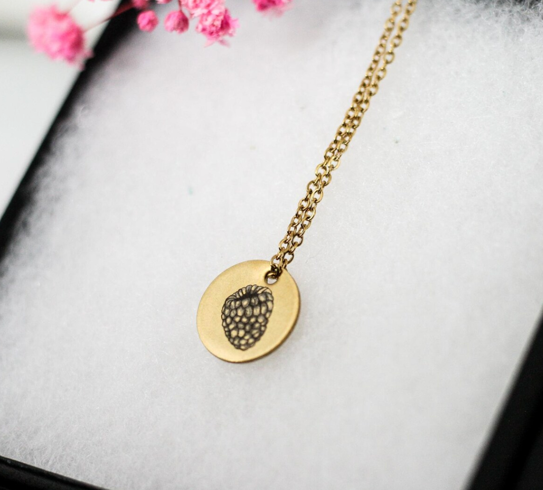 raspberry engraved onto gold pendant displayed on necklace box