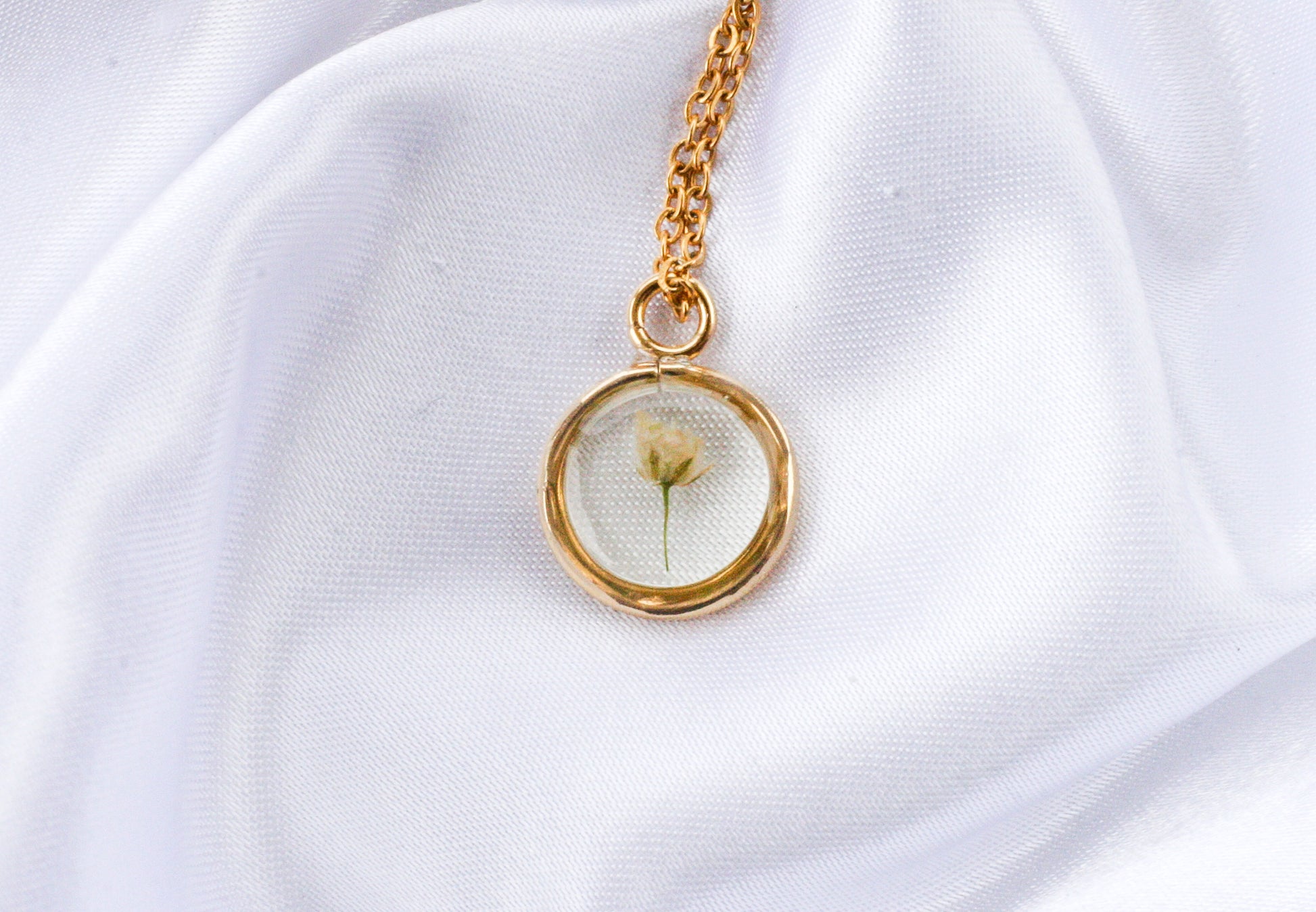 Gold necklace with one piece of babys breath inside.