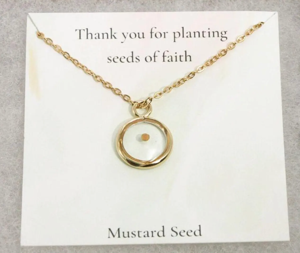 gold mustard seed necklace on top of a card reading 