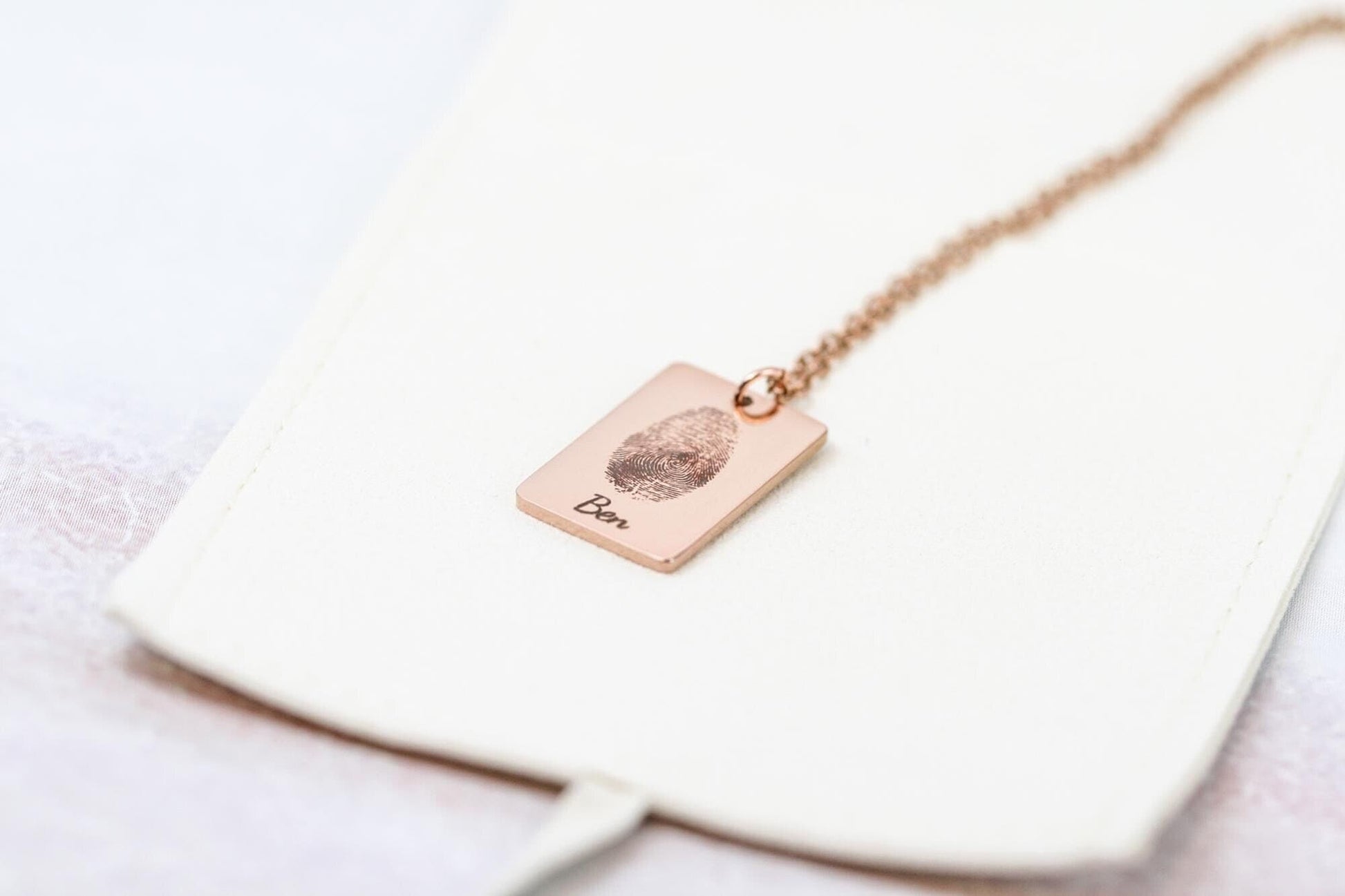 engraved fingerprint necklace  with the name "ben" in rose gold on a microfiber necklace bag