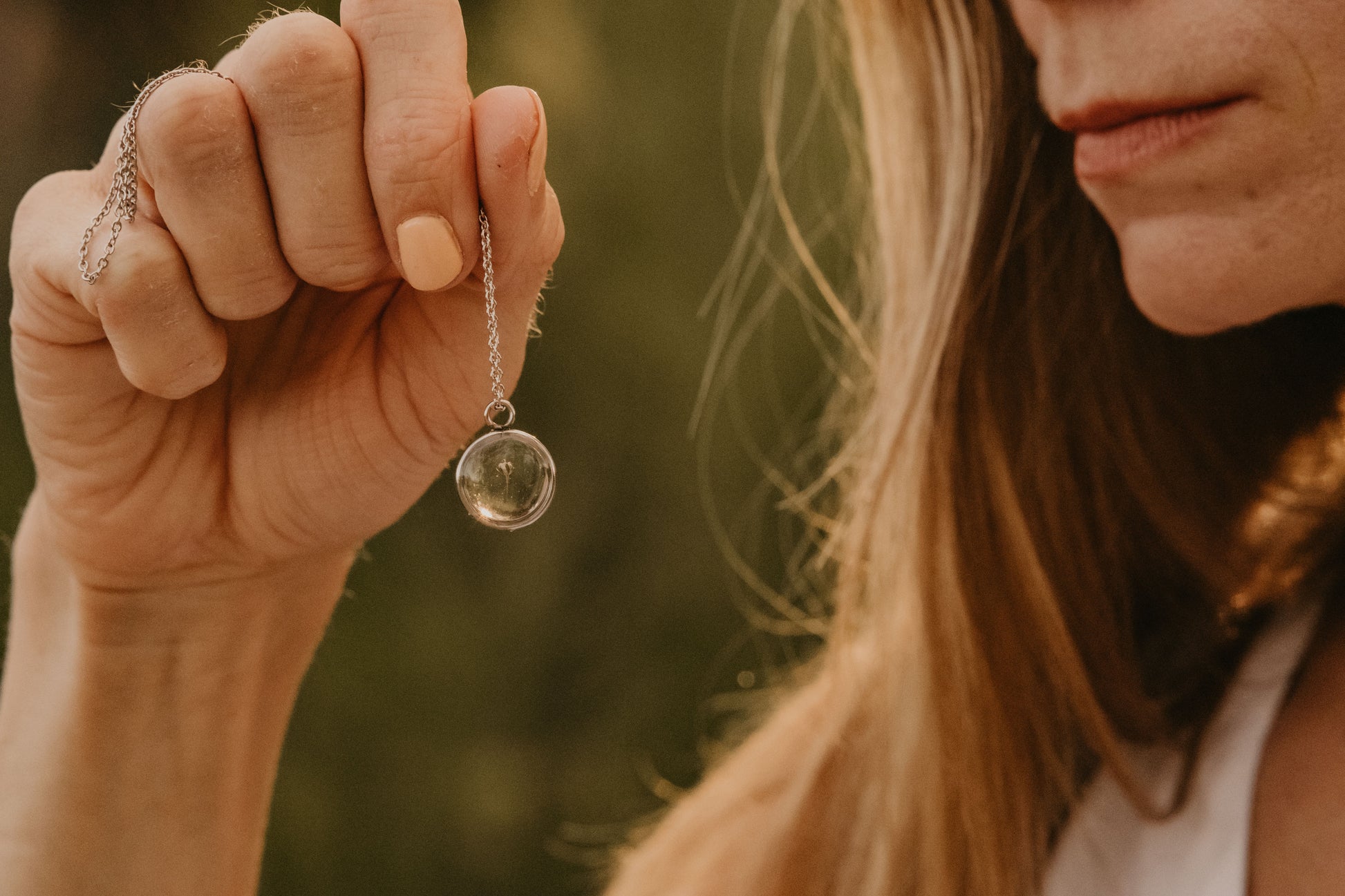 woman holding a silver babys breath necklace in the sunlight